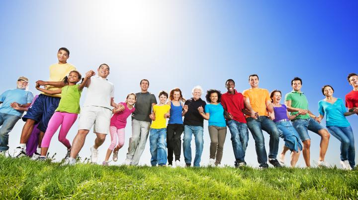 Large group of people holding hands in a field 